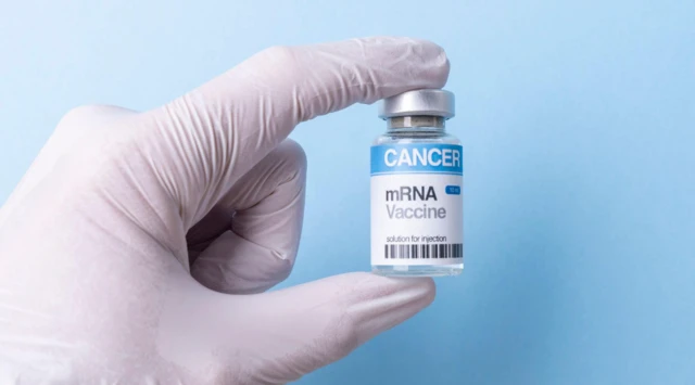 Mão com luva segura um frasco com rótulo “mRNA Vaccine” para câncer, em fundo azul, representando avanços na tecnologia de vacinas