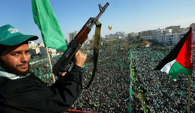 Homem palestino do Hamas mostra sua arma para apoiadores em um ato do Hamas em Gaza, em dezembro de 2007