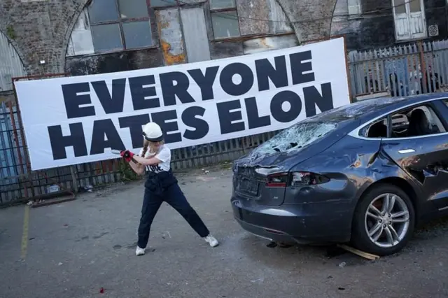 कारको पछाडिको भाग फुटाउन लागेजस्तो देखिने एक महिला