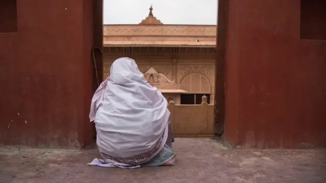 वृंदावनातील मंदिराकडे पाहणारी एक विधवा स्त्री