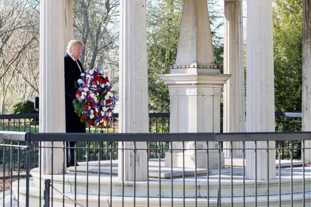 Trump com flores chegando ao túmulo