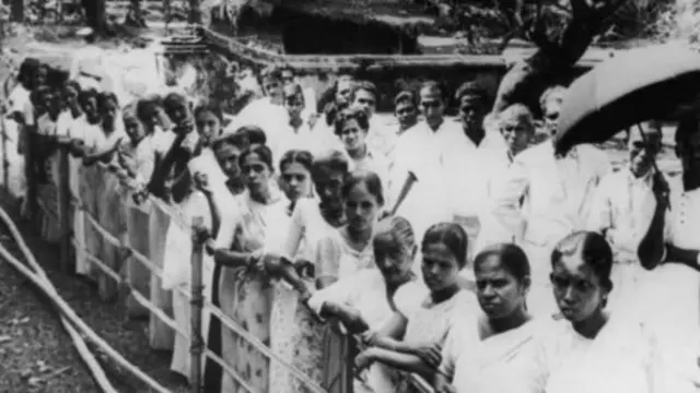 දශක කිහිපයකට පෙර ශ්‍රී ලංකාවේ අතීත ඡන්ද මධ්‍යස්ථානයක් ඉදිරිපිට පෙළ ගැසී සිටින ඡන්දදායකයන් පිරිසක්