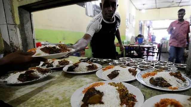 A Sri Lankan man serves a plate of rice and curry to a customer at a wayside cafe in Colombo on August 04, 2008.