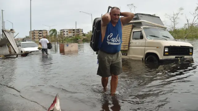 Un hombre carga su maleta en una calle inundada de Puerto Rico.