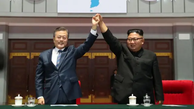 Kim Jong Un e Moon Jae-in erguendo as mãos juntos