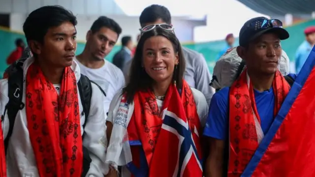 Kristin Harila sorrindo com bandeira da Noruega nos ombros