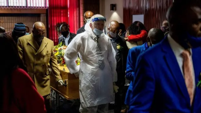 Un entrepreneur de pompes funèbres portant une combinaison de protection et un écran facial et des proches escortent le cercueil contenant les restes d'une victime du COVID-19 (nouveau coronavirus) lors d'une procédure funéraire dans un funérarium de Johannesburg, le 26 juillet 2020. - L'Afrique du Sud est le pays qui compte le plus grand nombre d'infections diagnostiquées en Afrique et se classe cinquième au monde après les États-Unis, le Brésil, l'Inde et la Russie.