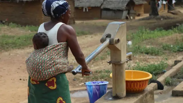 Une mère recueille de l'eau d'une pompe à Tuglor, dans le comté de Grand Gedeh
