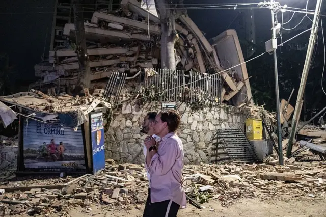 24 Haziran 2026'da Venezuela'nın Caracas kentinde meydana gelen şiddetli bir depremin ardından, bölge sakinleri çöken bir binanın enkazının yakınında duruyor.