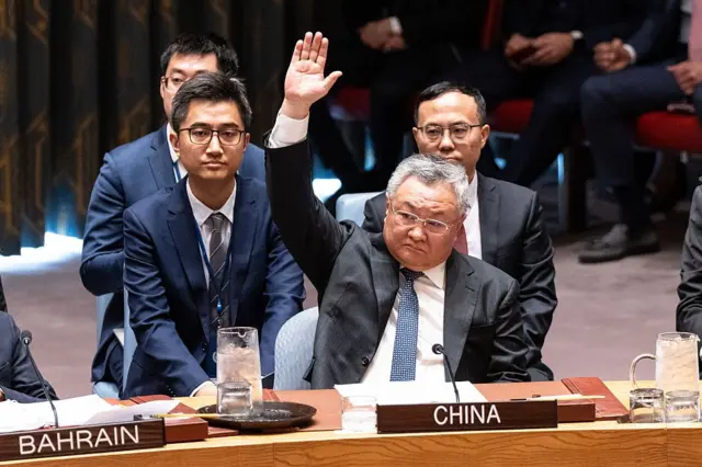Un hombre levanta la mano en una mesa con el rótulo con la palabra china en el Consejo de Seguridad de Naciones Unidas. Detrás de él hay varios hombres y a su derecha se ve un rótulo con la palabra "Bahrain".