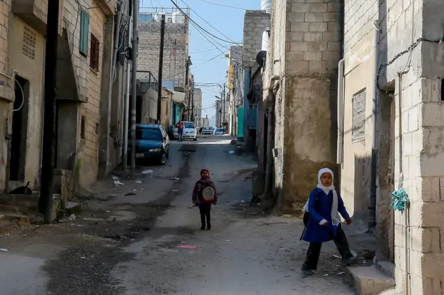 أطفال يسيرون في زقاق بمخيم للاجئين الفلسطينيين في جرش شمال عمّان، الأردن.