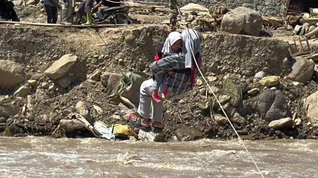 Khairunnisa bersama bayinya sedang melintasi sungai deras di Aceh Tengah. Jembatan yang dibuat secara "swadaya" ini tidak gratis. Setiap menyeberang para penyintas harus merogoh kocek Rp30.000.