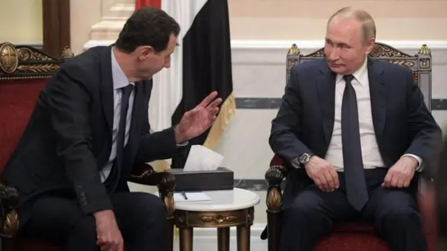 O ex-presidente da Síria, Bashar al-Assad, sentado ao lado do presidente da Rússia, Vladimir Putin, ambos de terno preto, em Moscou