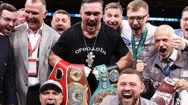 Олександр Усик позує з чемпіонськими поясами та членами своєї команди після перемоги над Даніелем Дюбуа
