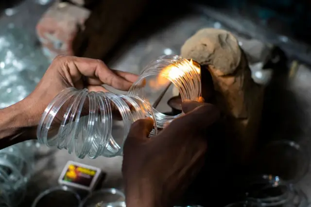 Seorang pekerja membuat gelang kaca di bengkel rumah di Firozabad.