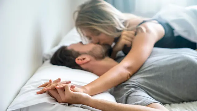 Молода пара, що цілується в ліжку — стокове фото