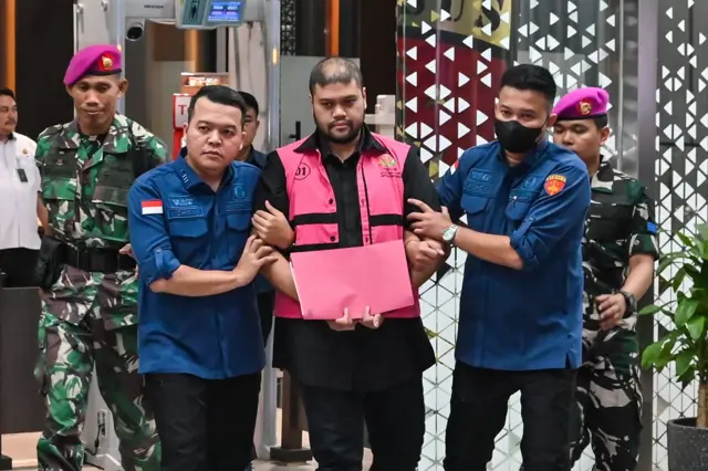 Tersangka kasus dugaan tindak pidana korupsi tata kelola program Makan Bergizi Gratis (MBG) Glory Harimas Sihombing (tengah) berjalan menuju mobil tahanan di Kejaksaan Agung, Jakarta, Kamis (18/6/2026). Kejaksaan Agung menyatakan terus menelusuri orang-orang yang terlibat dalam korupsi program jagoan Prabowo-Giran ini.