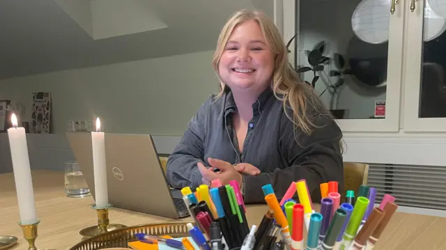 Johanna Göransson sentada com seu laptop e sorrindo para a câmera