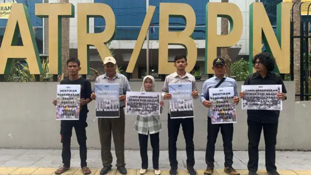Sejumlah warga Air Bangis dan aktivis lingkungan memegang poster di depan gedung Kementerian ATR/BPN untuk memprotes perampasan lahan rakyat.
