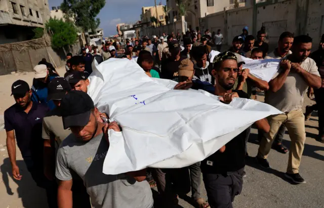 خارج مستشفى ناصر في خان يونس، فلسطينيون يشيعون جثامين من قُتلوا فجر الجمعة في غارات إسرائيلية على خيم وعلى أفراد كانوا يسعون للحصول على مساعدات