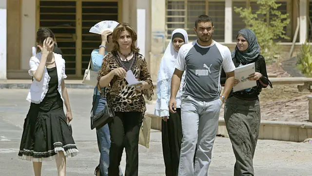 أحد الطلاب يسير مع مجموعة من زميلاته الطالبات في كلية التكنولوجيا بجامعة بغداد بينما تمسك بعضهن بدفاترهن
