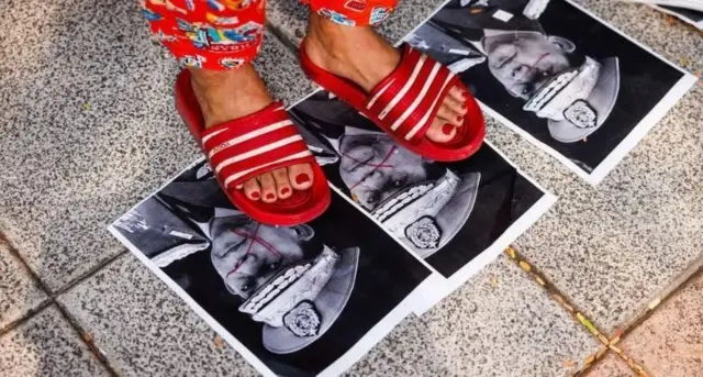 મ્યાનમારના લશ્કરી શાસકોના ફોટા પર પગ મૂકીને વિરોધ કરી રહેલાં એક મહિલા