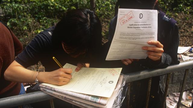 香港湾仔人民入境事物大楼外两名正在排队等候的女子填写归化英国属土公民表格（29/3/1996）
