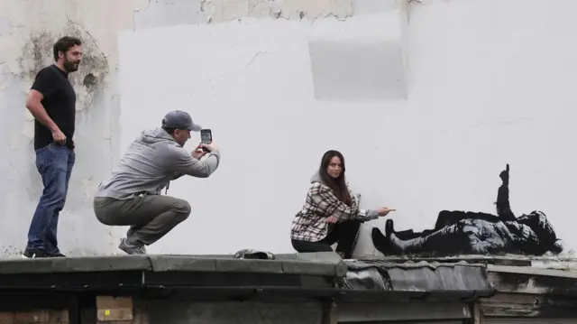 Люди позируют возле нового произведения Бэнкси в лондонском районе Бейсуотер