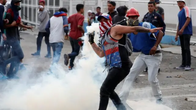 Hombres con la cabeza tapada arrojando gases.