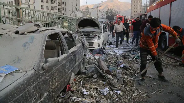 Ciudadanos iraníes recogen escombros en Teherán.