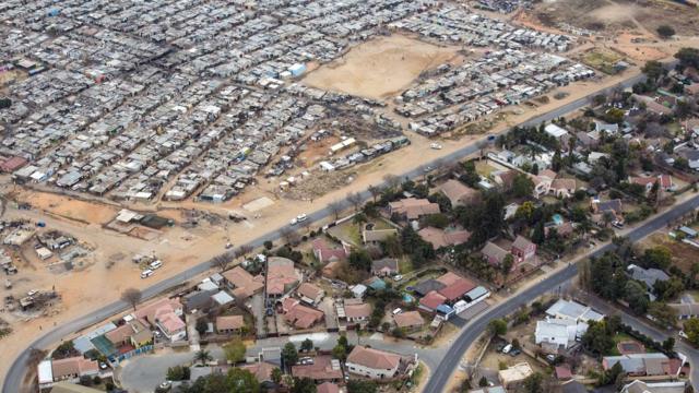 Una carretera divide el barrio de clase media de Bloubusrand, en Johannesburgo, del campo Kya Sands, hogar de muchos inmigrantes.