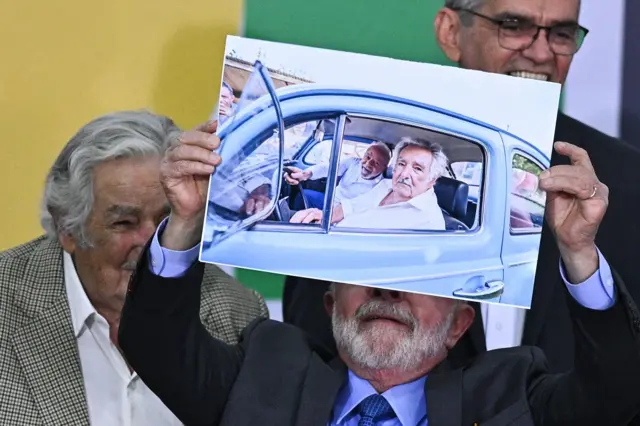 لولا در کنار پپه و در حالی که عکس او در فولکس قورباغه ای رئیس جمهور اروگويه را بالای سر برده است