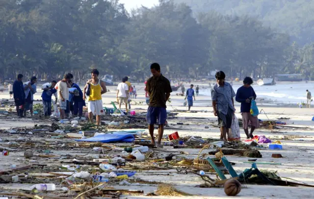 Pessoas caminham entre escombros ao longo da costa da praiaapp de aposta copaPathong, na ilhaapp de aposta copaPhuket, sul da Tailândia,app de aposta copa27app de aposta copadezembroapp de aposta copa2004, um dia depois que um maremoto devastou a costa