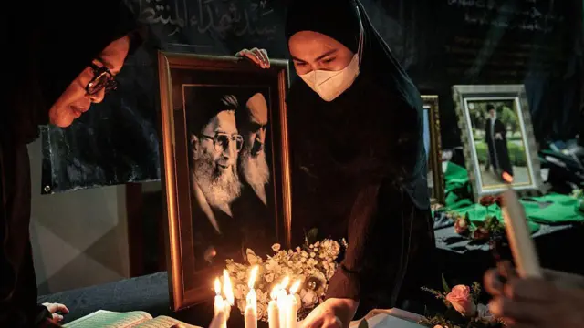 Seorang wanita Muslim memegang potret Pemimpin Tertinggi Iran Ali Khamenei (kiri), yang memimpin Iran sejak 1989 dan tewas dalam fase awal operasi militer skala besar AS dan Israel, saat area belasungkawa disiapkan di Pusat Kebudayaan Islam Jakarta di Jakarta pada 1 Maret 2026.
