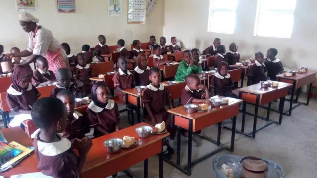 Iya olounjẹ kan n pin ounjẹ fun awọn akẹkọ ileẹkọ alakọbẹrẹ ni kilaasi wọn