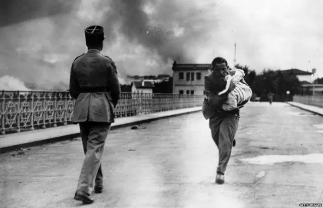 Journalist Raymond Walker risks his life under a hail of bullets dashing across the international bridge from Hendaye, France, to Irun, Spain to save a baby, during the Spanish Civil War