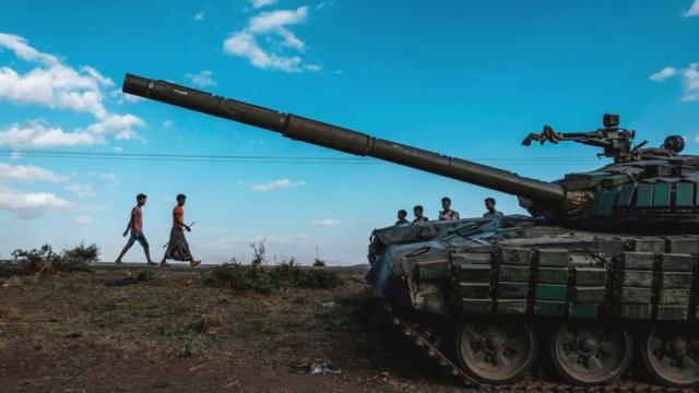 شبّان يسيرون بجوار دبابة مهجورة تابعة لقوات تيغراي جنوب بلدة مهوني، إثيوبيا