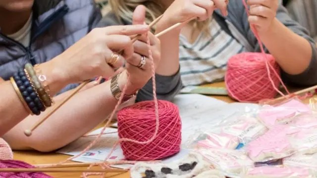 Mujeres tejiendo gorros rosas.
