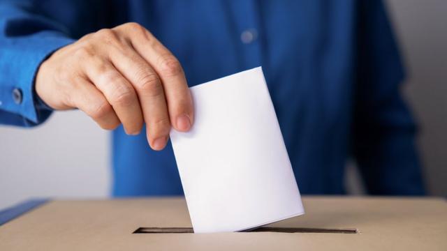 Pessoa colocando voto em urna