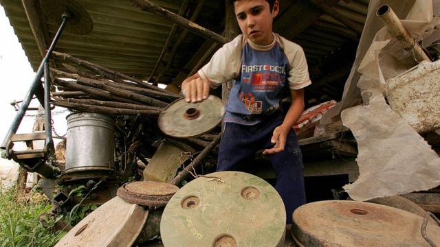 Um garoto segura minas terrestres desativadas na Croácia