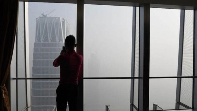 Hombre mirando la nube de contaminación en Pekín.