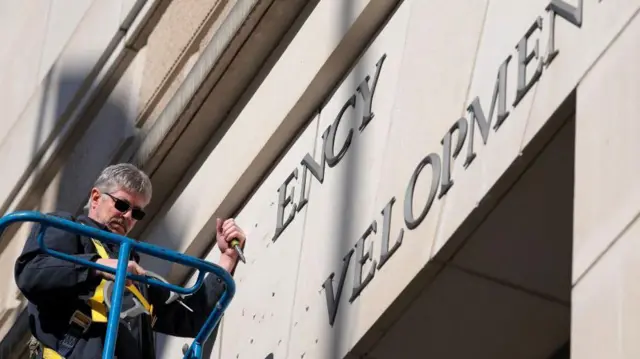 Un trabajador arranca con un cincel las letras de USAID de su fachada.