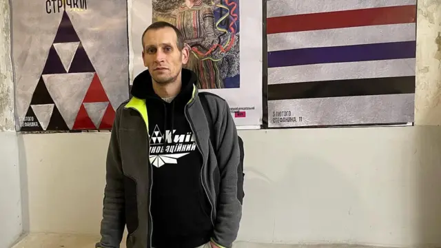 Давид Чичкан на фоні анонсу про відкриття однієї із його виставок