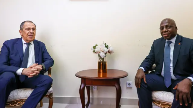 Два мужчины в костюмах сидят за столом