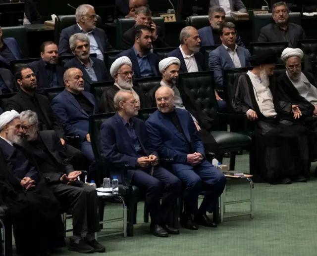 علی لاریجانی و محمد باقر قالیباف در یک مراسم در کنار هم نشسته‌اند و هم در حال گفت و گو هستند، تعدادی دیگر از مقامات در عکس دیده می‌شوند