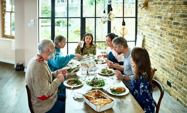 خانواده‌ای با هم بر سر میز غذا می‌خورند