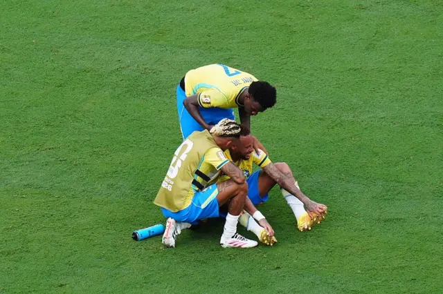 Neymar no campo sendo consolado por outros jogadores