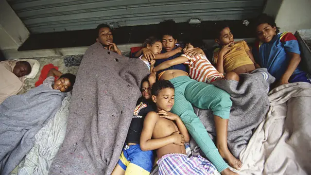 Niños de la calle durmiendo juntos. Una adolescente abraza a dos niños pequeños.