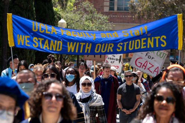 Algunos docentes y empleados de la UCLA marchan bajo una pancarta que reza 