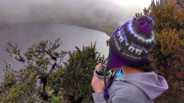 Mujer toma café frente a una laguna en lo alto de una montaña. (Foto: Liliana X. González)